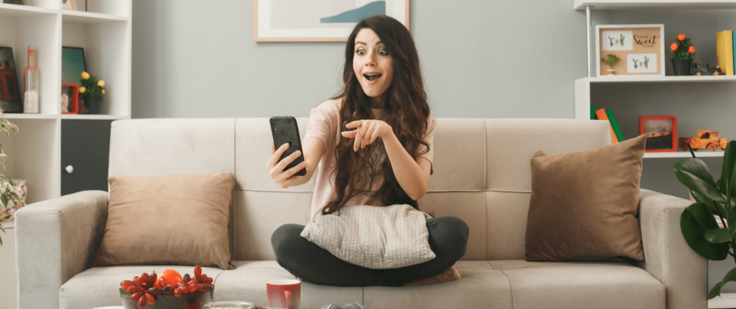 Image of a woman looking excitedly at her phone, depicting interesting ways to use a smart home.